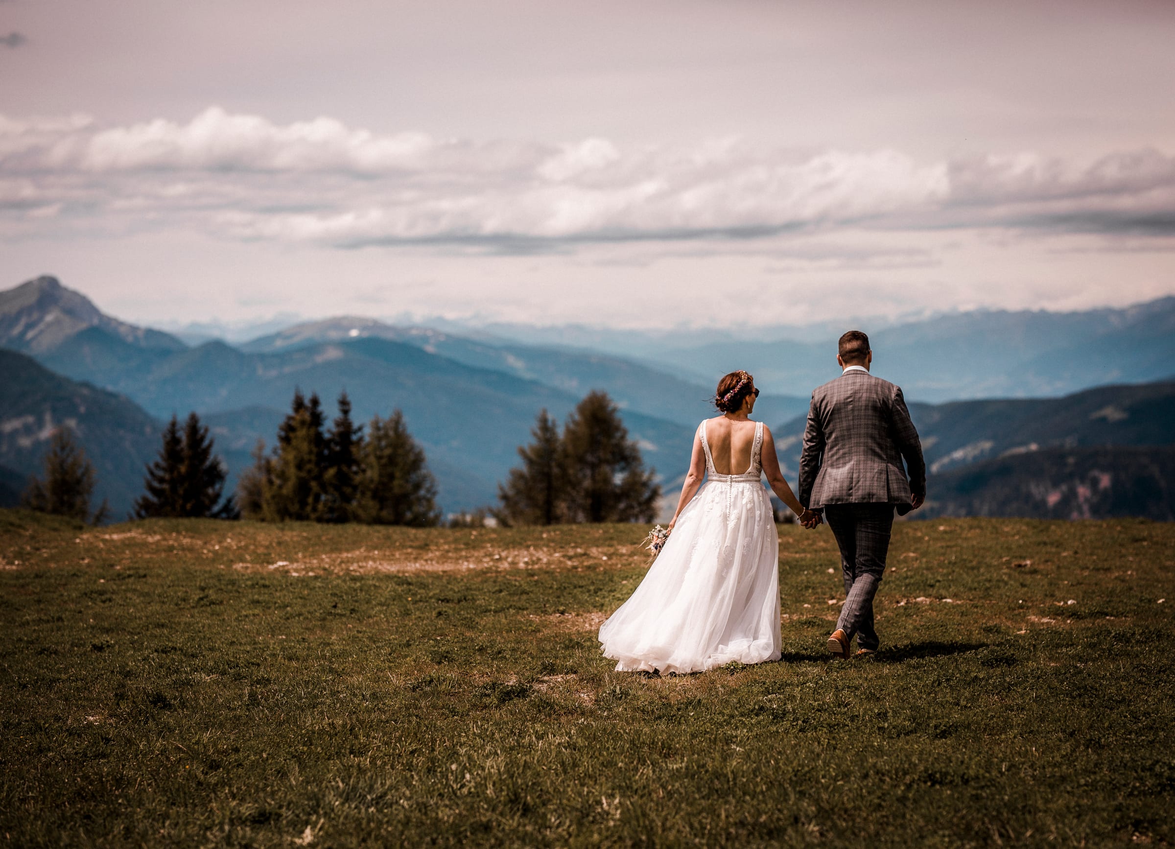 Brautpaar Hand in Hand auf Almwiese mit Lienzer Dolomiten im Hintergrund
